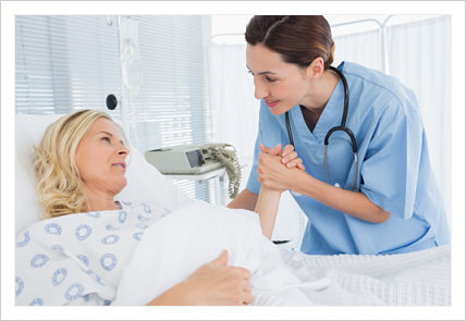 Picture of a Nurse (Female) holding a Patient&apos;s (Female) hand while she is lying down