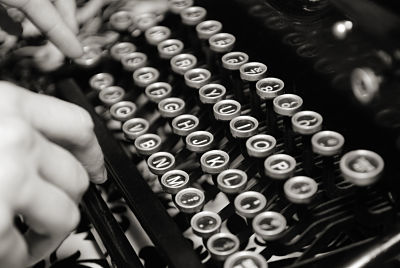 Picture of a typewriter with someone typing on it.